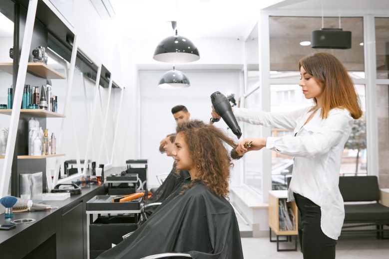 female-hairstylist-drying-curly-girl-s-hair-using-big-plastic-brush